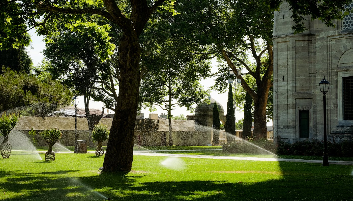 Lush green lawn courtyard with water sprinklers running on sunny day